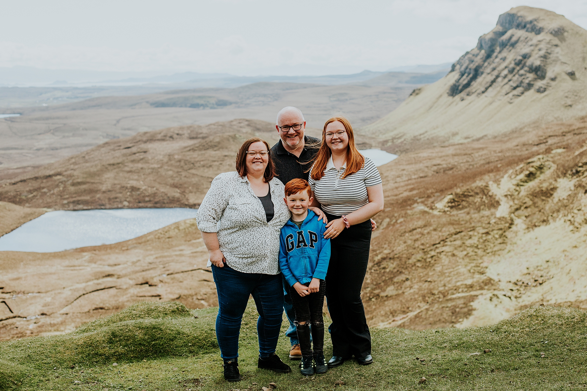 Family of four smiling for a photo at the quiraing on the isle of skye