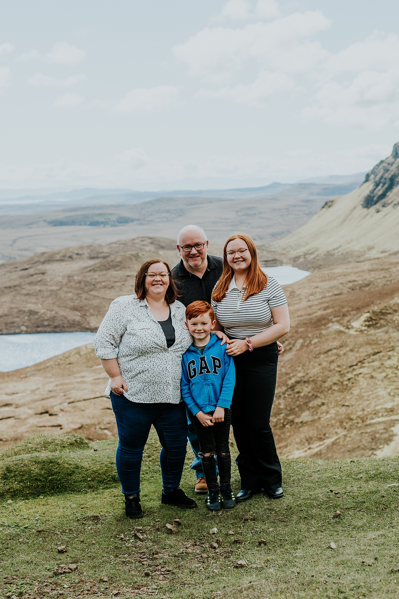 family of four smiling overlooking some lochs at the quiraing on the isle of skye
