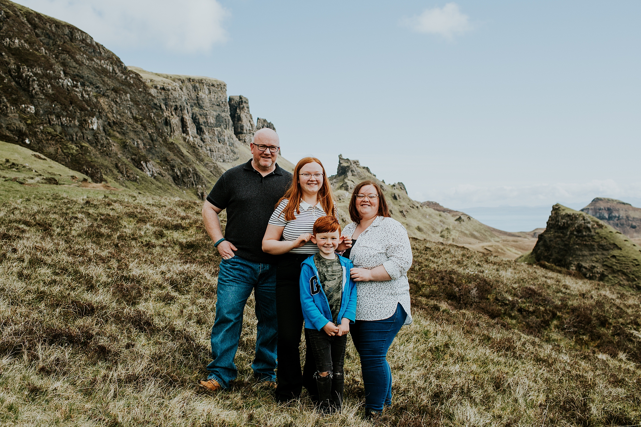 family of four smiling at the quiraing on the isle of skye, sister pulling brothers ears