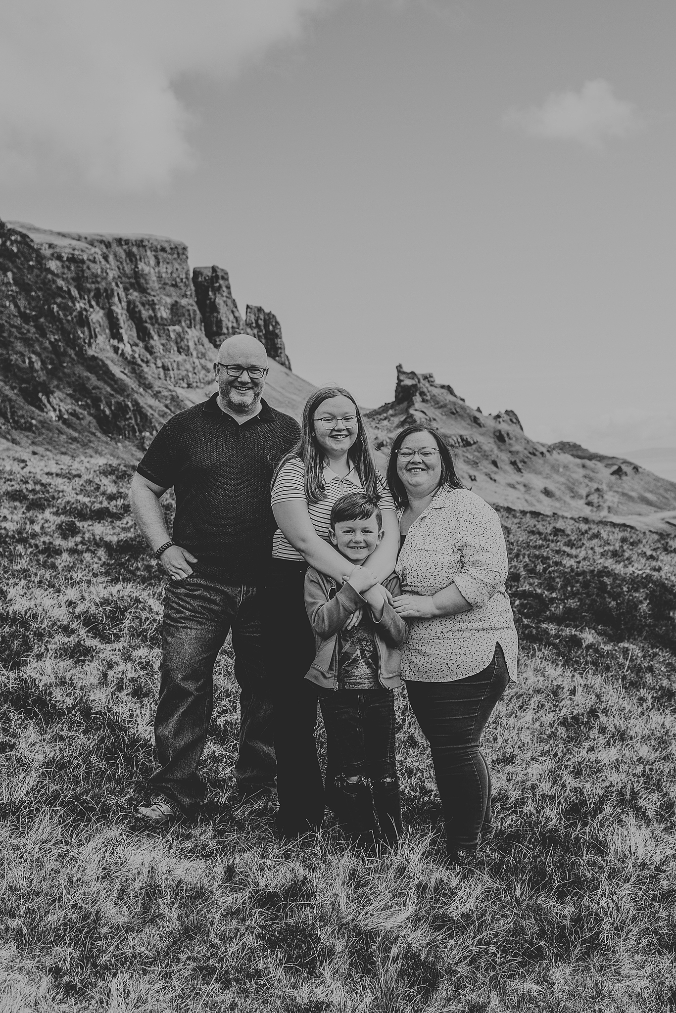 black and white photo of family hugging at the quiraing on the isle of skye