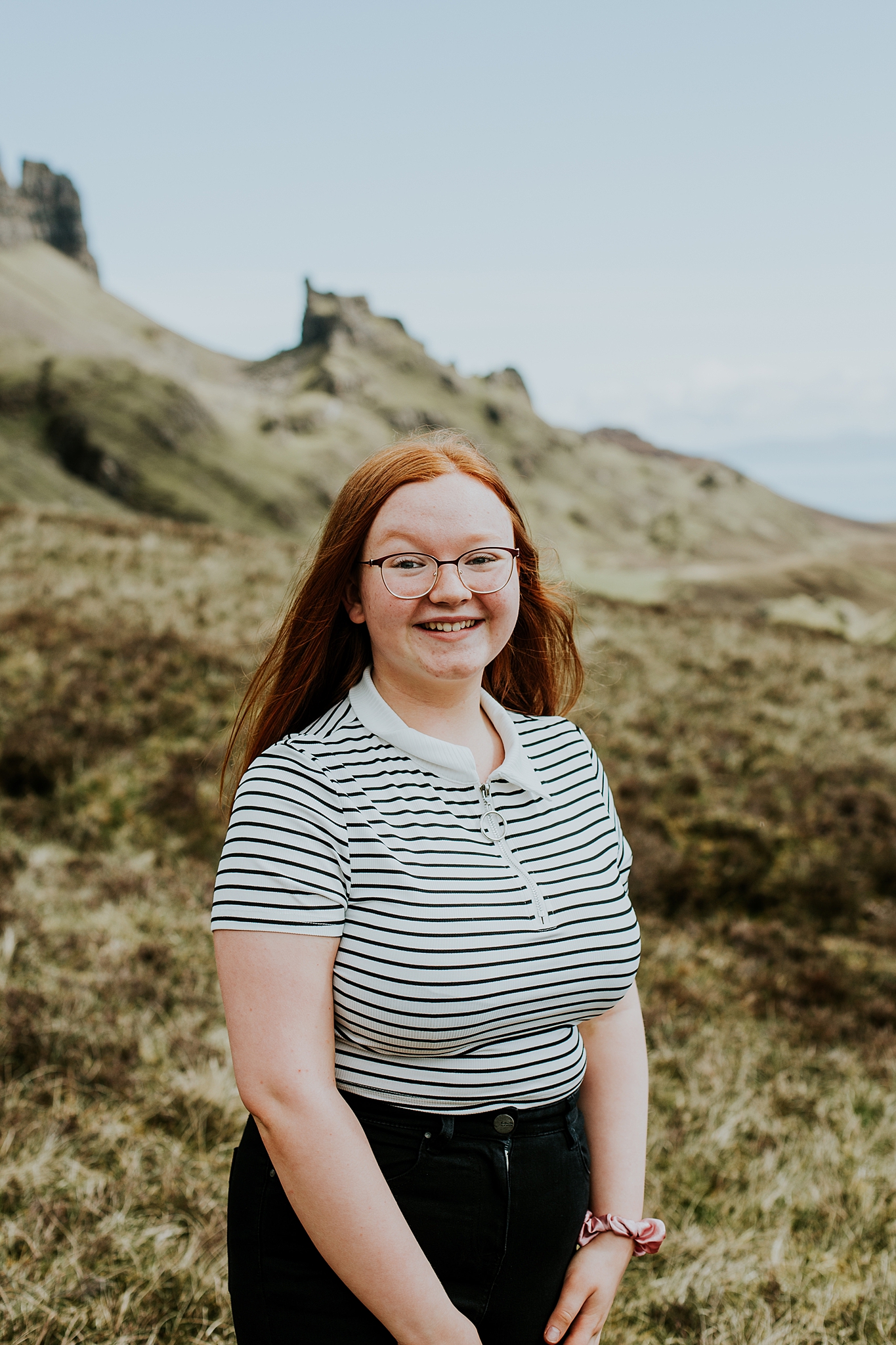 beautiful yound red headed girl smiling with the quiraing in the background on the isle of skye