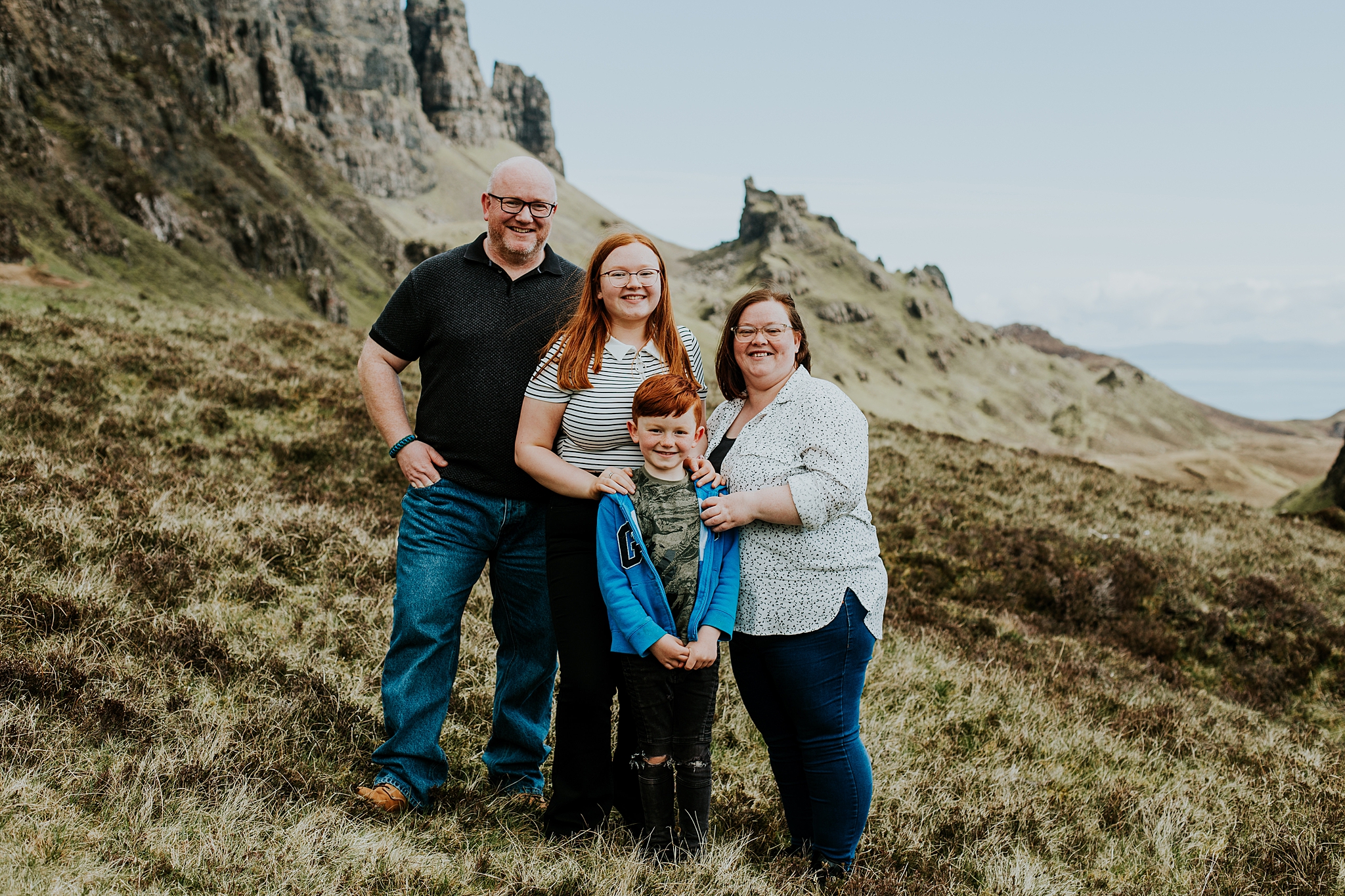 family of four hugging and smiling at the quiraing on the isle of skye