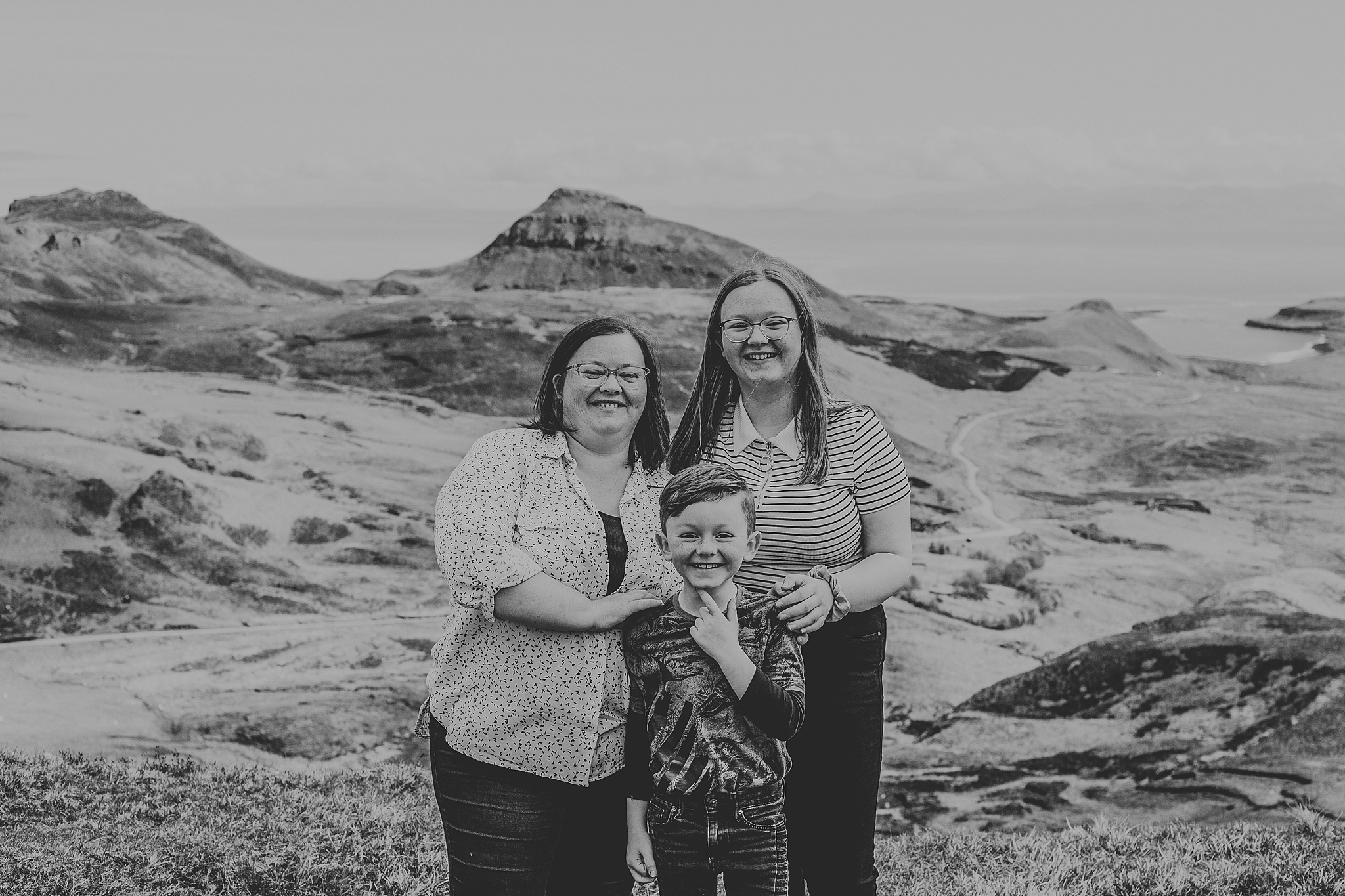 black and white photo of mum and two children smiling at the quiraing for and isle of skye family photoshoot