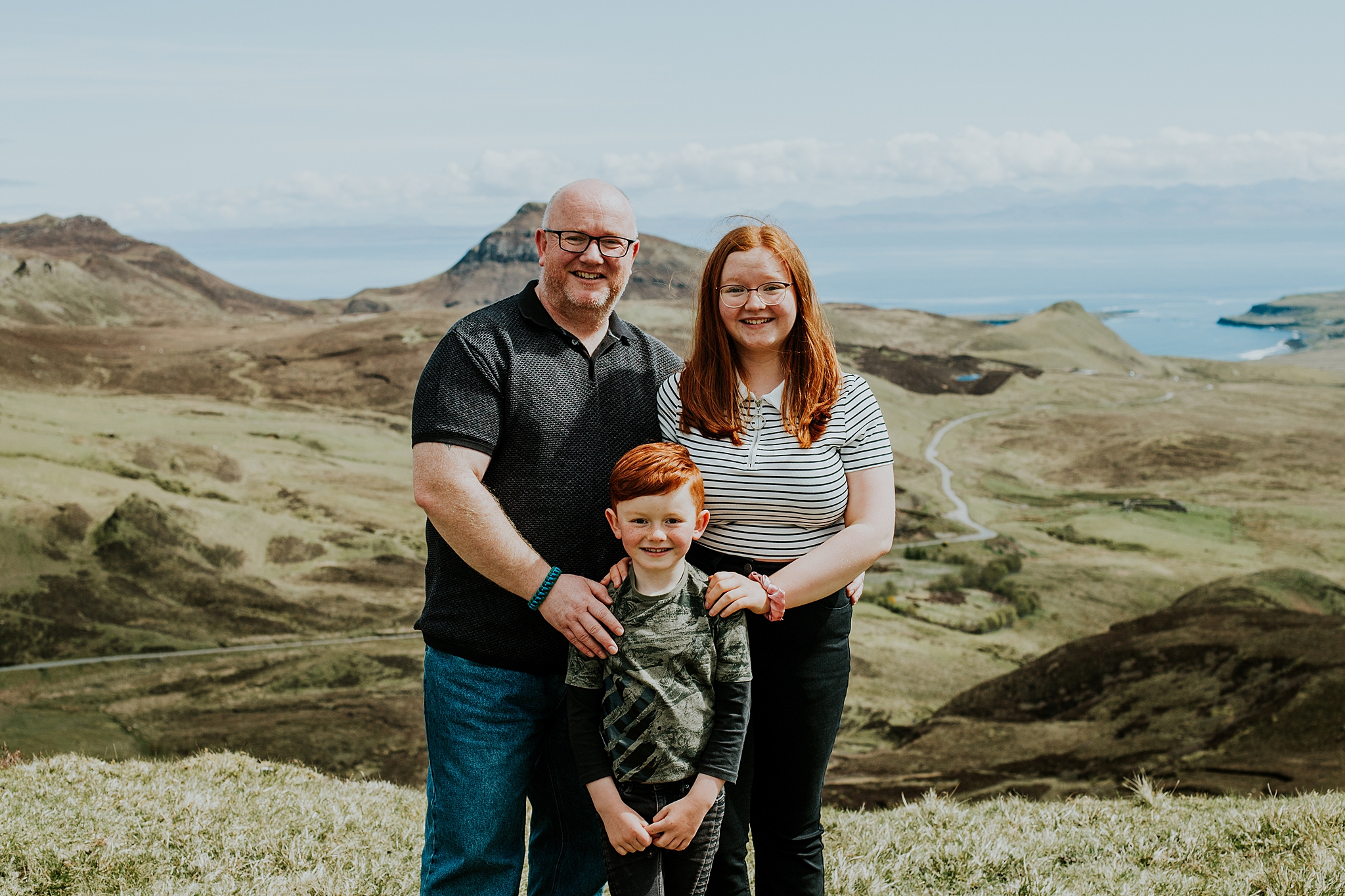 dad with his two beautiful red headed children smiling at the quiraing on the isle of skye